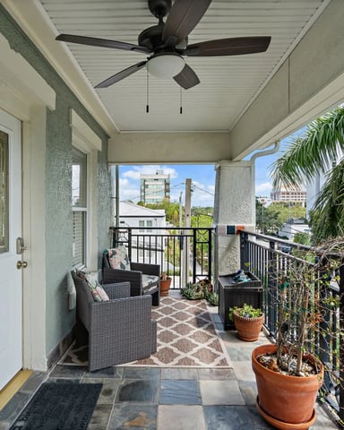 Two-story white Mediterranean-style house with arched entryway, palm trees, and manicured front yard